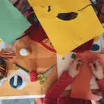 Kinderhände bei einer herbstlichen Bastelaktivität als Inspiration für Fingerspiele