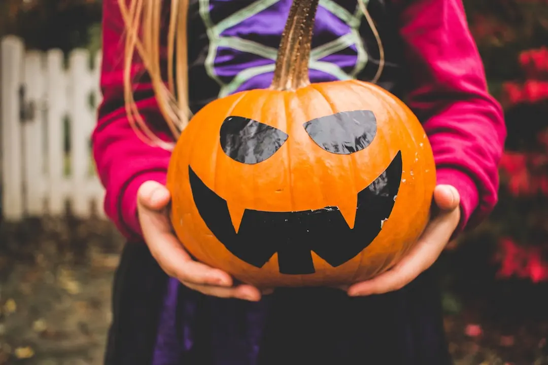 Halloween-Spiele für Kinder: 25 lustige Ideen für Kita, Schule und Zuhause 2 Kind mit Halloween-Kürbis als Inspiration für Halloween-Spiele